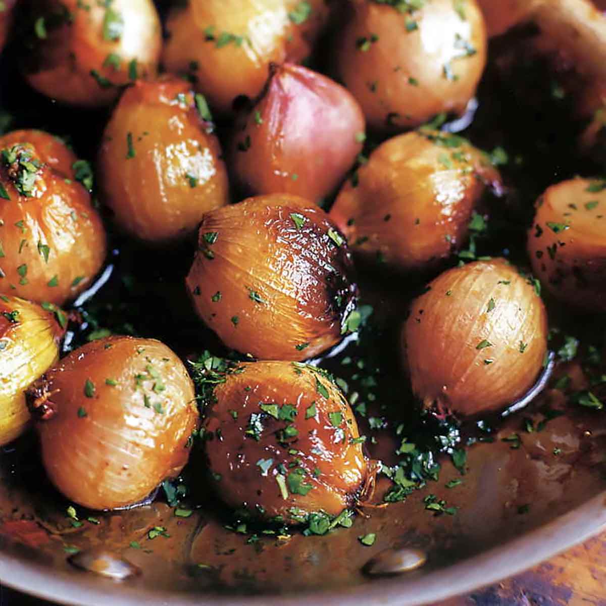 A skillet full of Ina Garten's caramelized shallots, garnished with parsley.