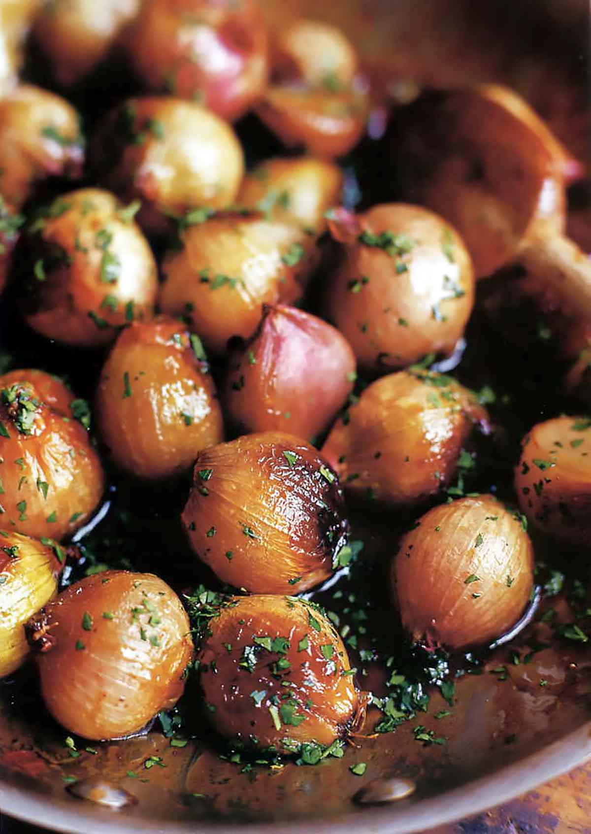 A skillet full of Ina Garten's caramelized shallots, garnished with parsley.