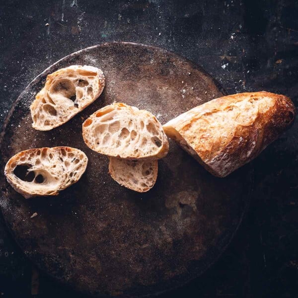 Jim Lahey's no-knead baguett with a few slices cut from it on a wooden board.