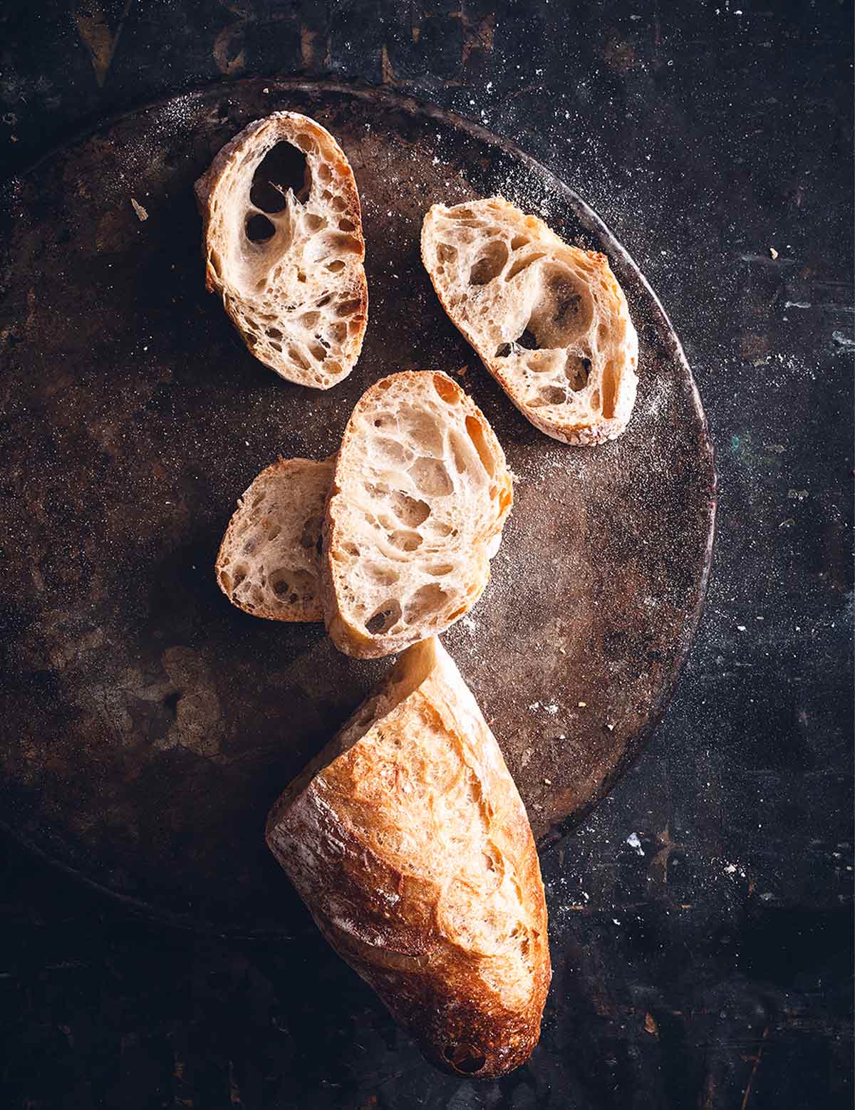 Jim Lahey's no-knead baguett with a few slices cut from it on a wooden board.