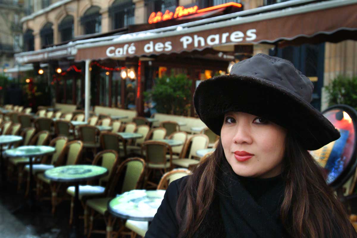 An image of Kim Sunée outside a cafe in France.