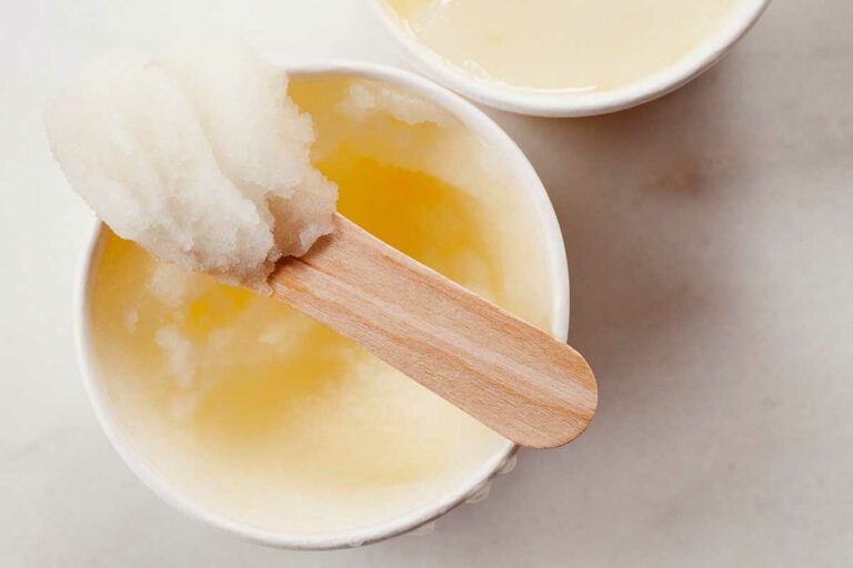 Two small bowls of lemon ice, with a wooden popsicle stick resting on top of one.