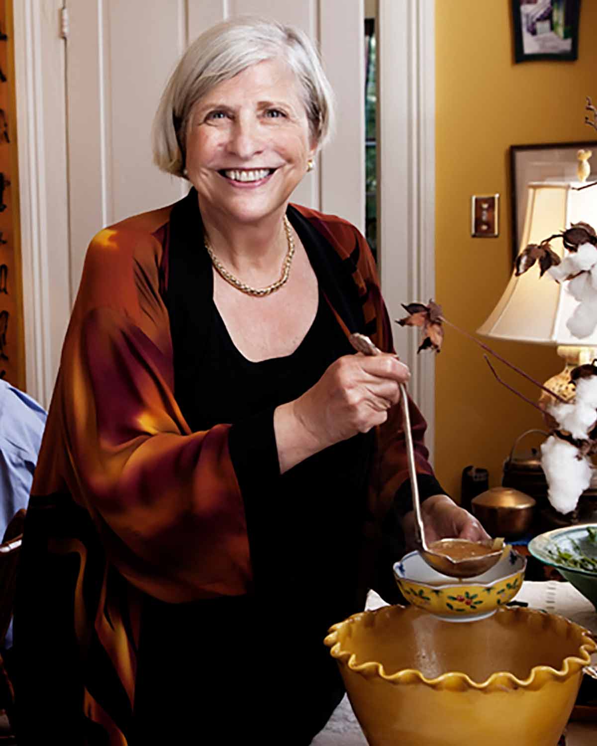 A photo of Nathalie Dupree ladling soup into a bowl.