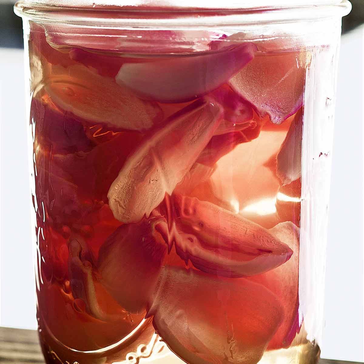 A Mason jar filled with pickled shallots, submerged in brine.