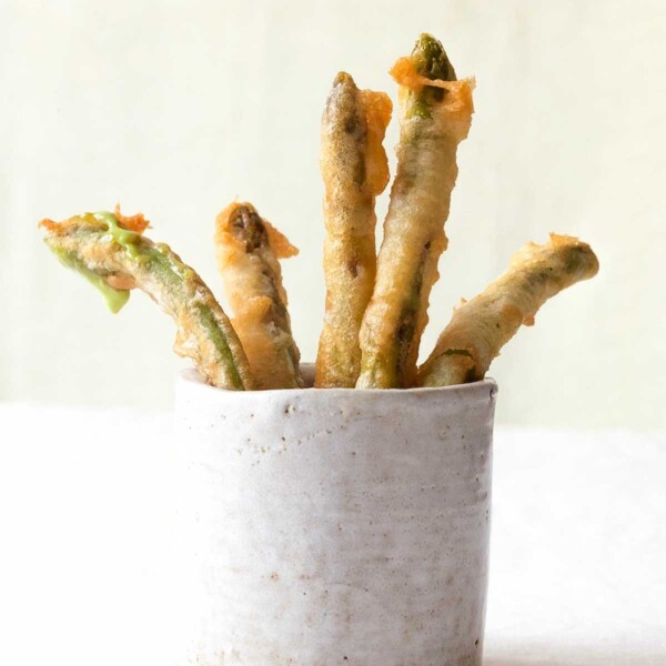 Five Portuguese deep-fried green beans standing in a white cup.