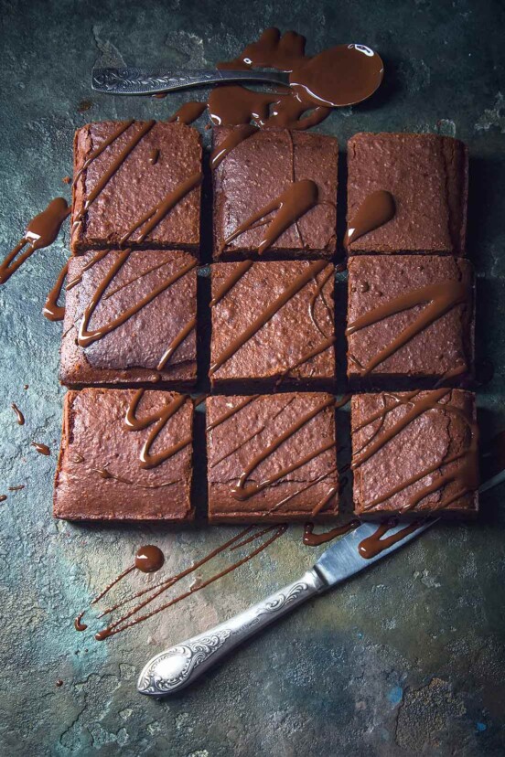 A pound of chocolate cake cut into nine squares and drizzled with chocolate ganache.