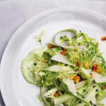 A tangle of raw asparagus salad, pine nuts and frisee on a green dressing.