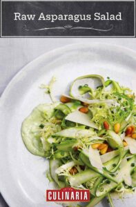 A tangle of raw asparagus salad, pine nuts, and frisee on top of a green dressing.