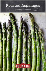 Ten spears of asparagus seasoned with salt and pepper and arranged in a row on a baking sheet.