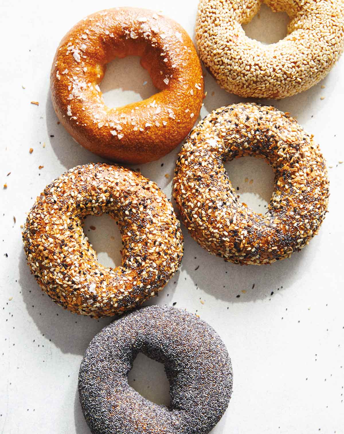 Five rye bagels with assorted toppings on them.