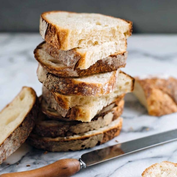 Halved slices of sourdough stacked on top of each other on a white and grey marble surface.