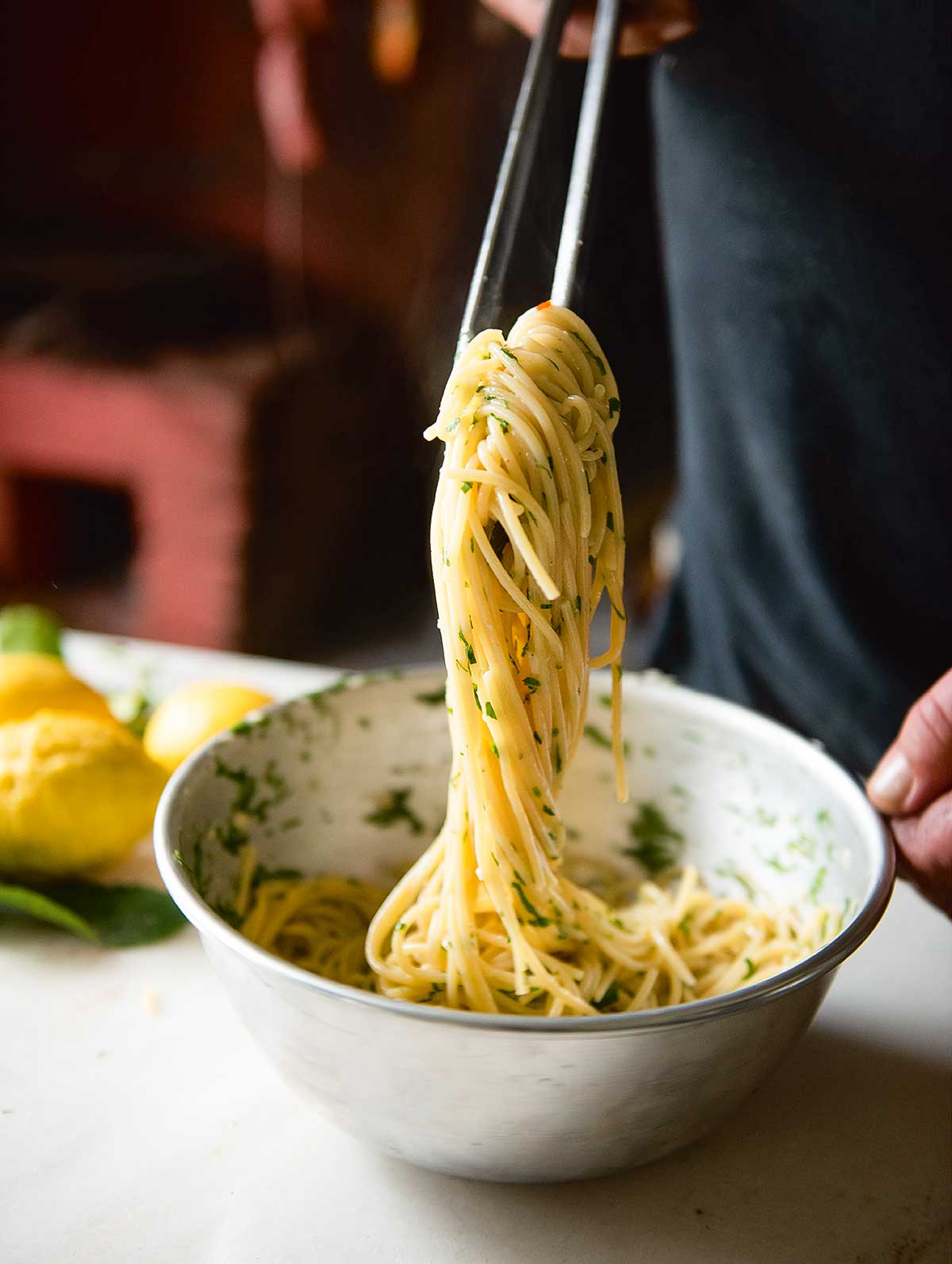 En person som använder metallätpinnar för att ösa upp spagetti al limone amalfitano ur en skål.