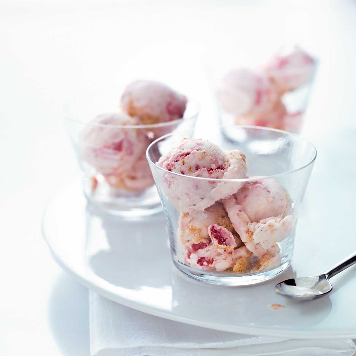 Three glass bowls filled with scoops of strawberry cheesecake ice cream.