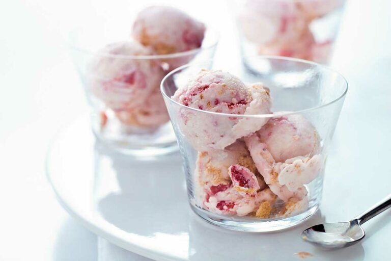 Three glass bowls filled with scoops of strawberry cheesecake ice cream.
