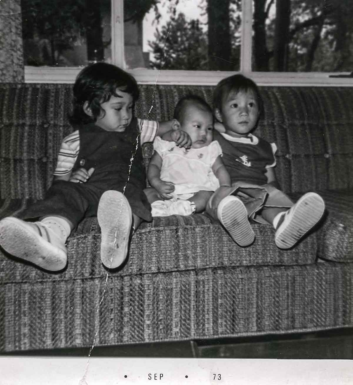 A photo of Kim Sunee as a child on a couch with two other children.