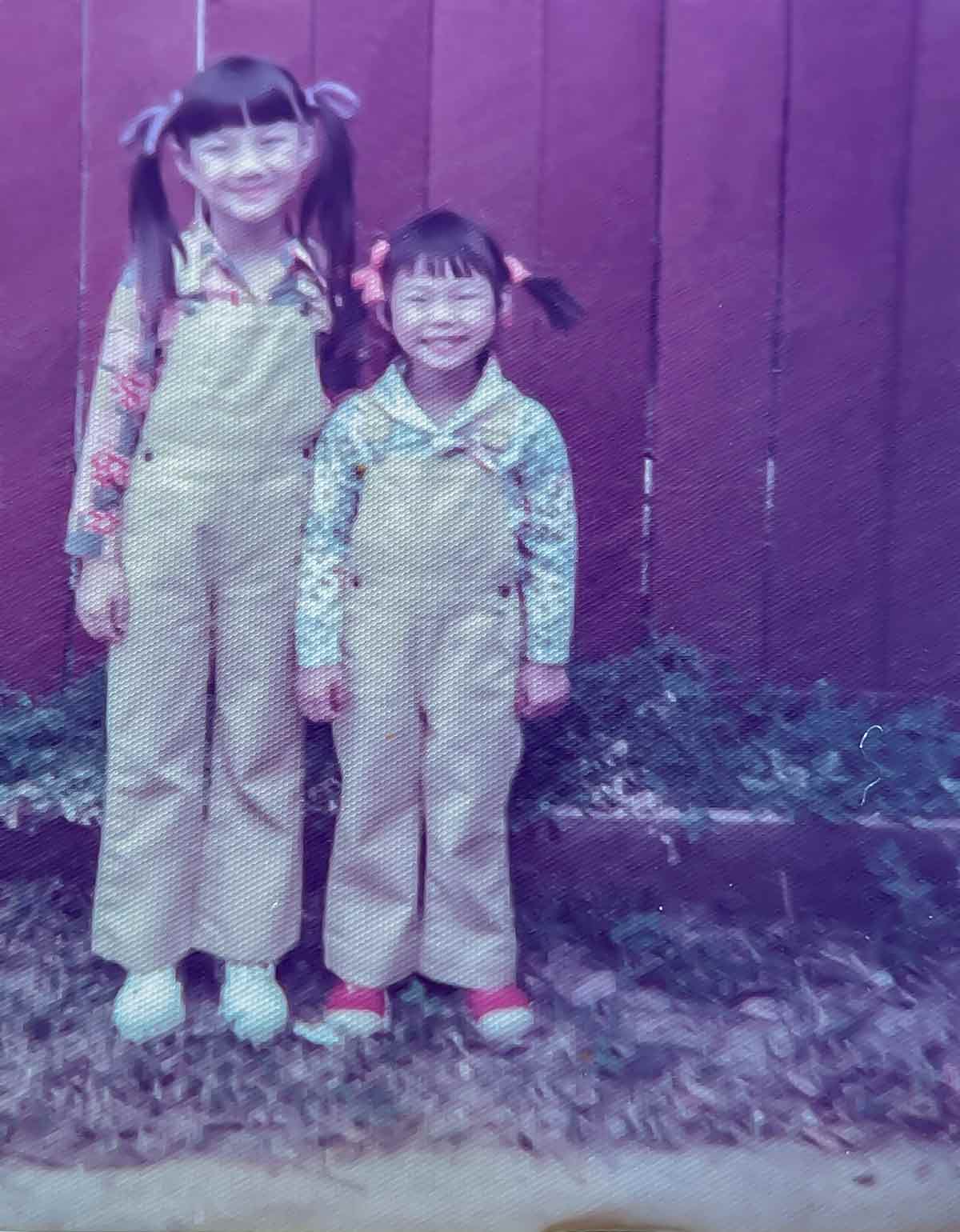 Kim Sunée posing with her sister for a photo as a child.