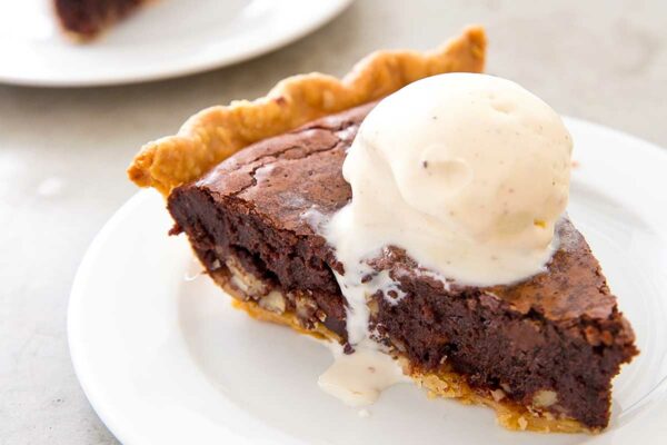 Slices of tar heel pie on individual white plates, each topped with a scoop of vanilla ice cream.