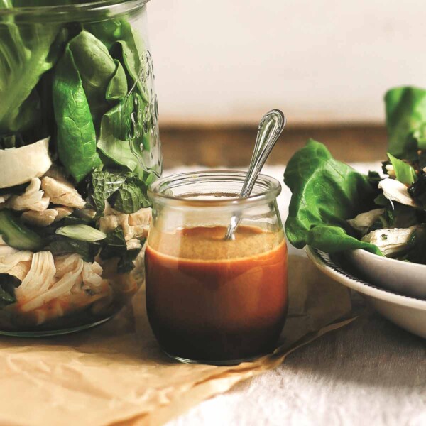 A small jar of Thai-inspired peanut dressing next to a bowl and jar of chicken salad.