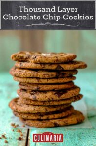 Stack of 10 chocolate chip cookies, each topped with sea salt on an aqua piece of wood