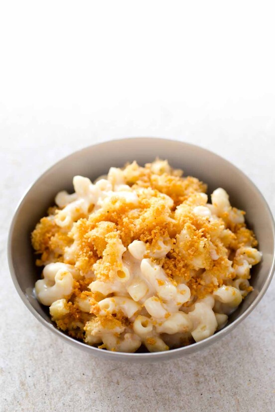 A grey ceramic bowl filled with baked mac and cheese with bread crumbs