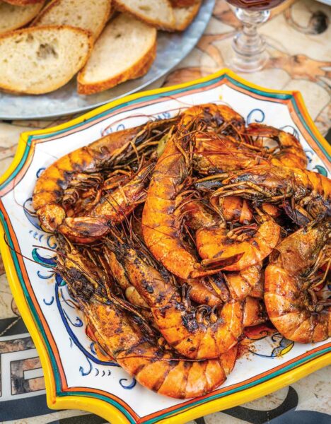 A platter of baked shrimp with Creole sauce with bread slices on the side.