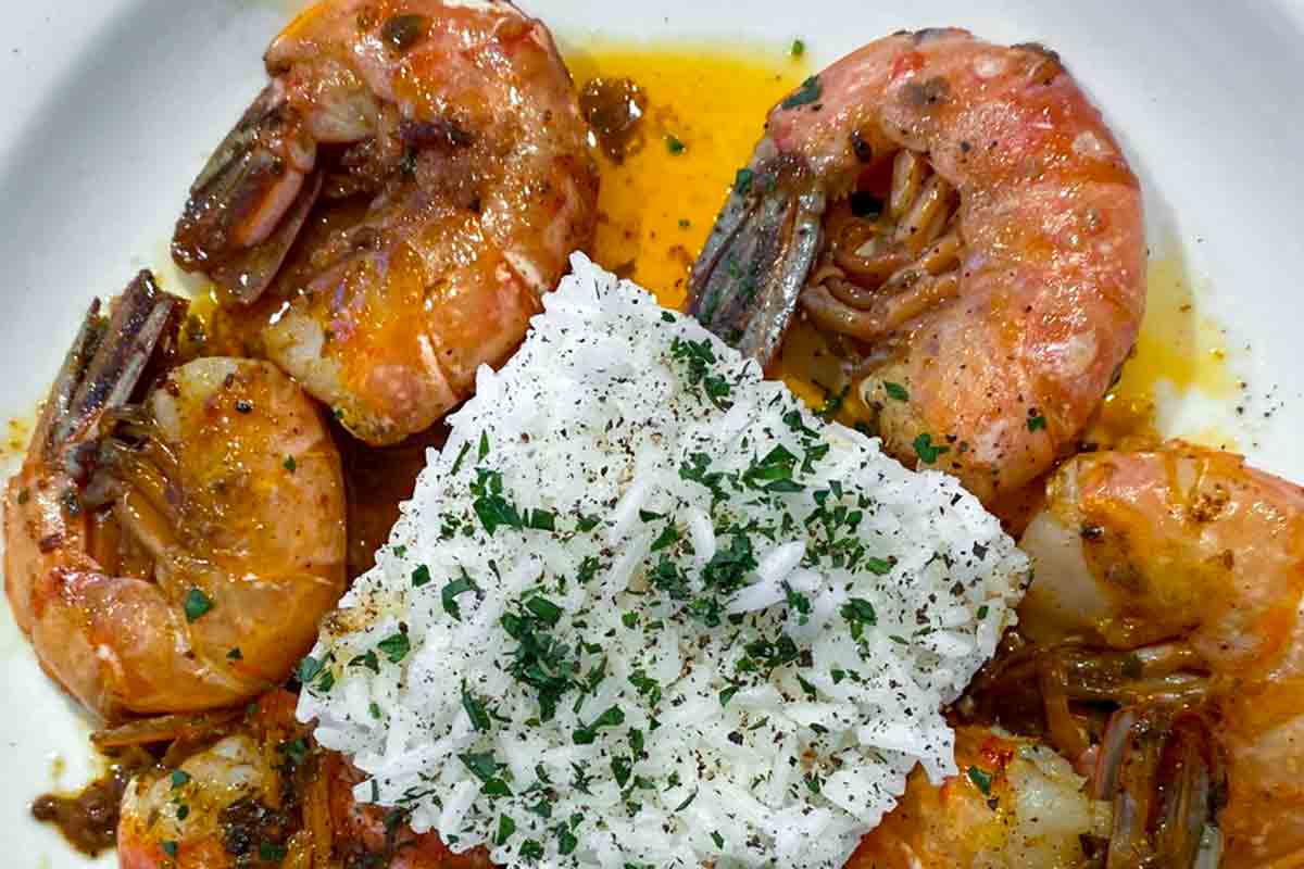 A bowl of baked shrimp with Creole sauce with a block of rice in the center.