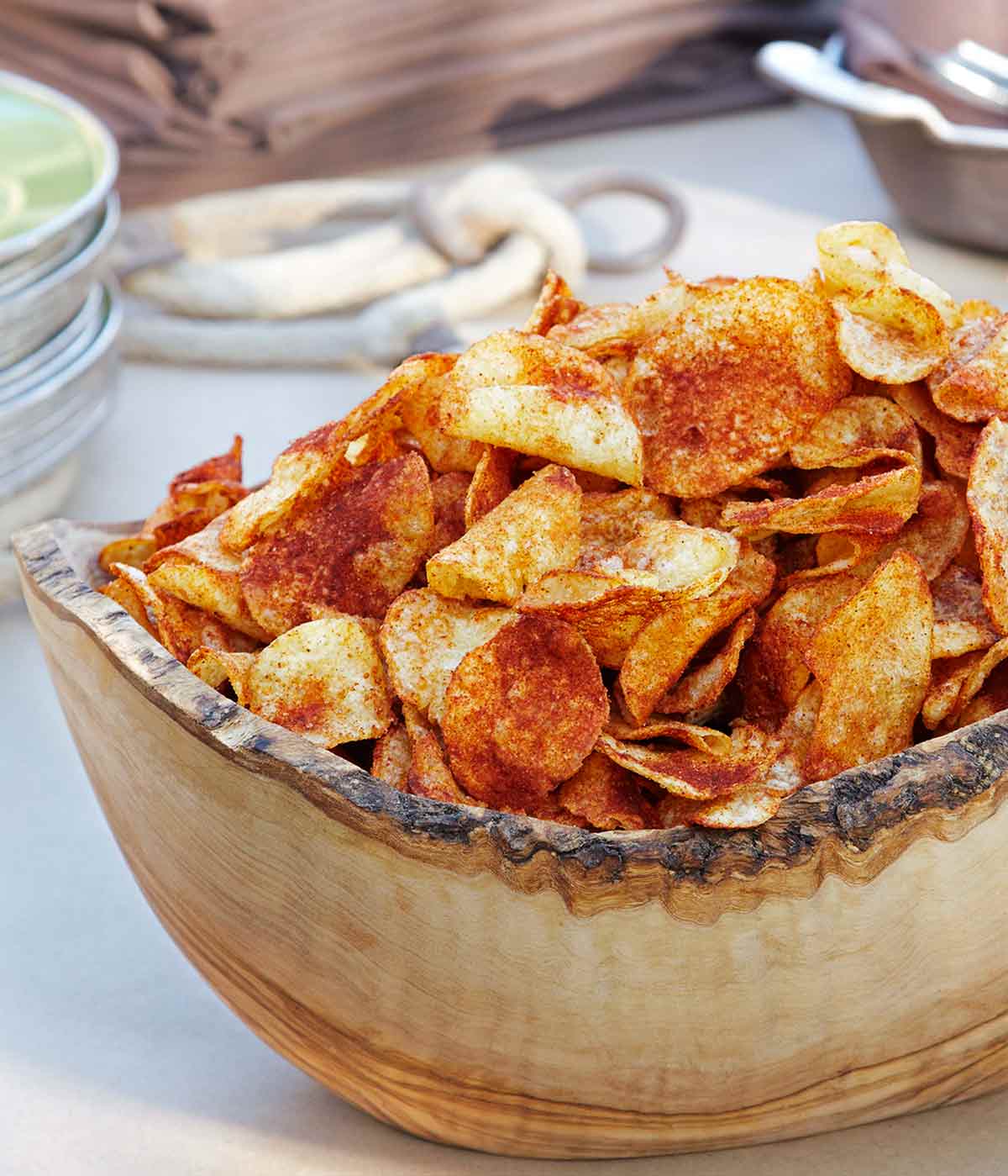 A carved wooden bowl filled with barbecue potato chips.