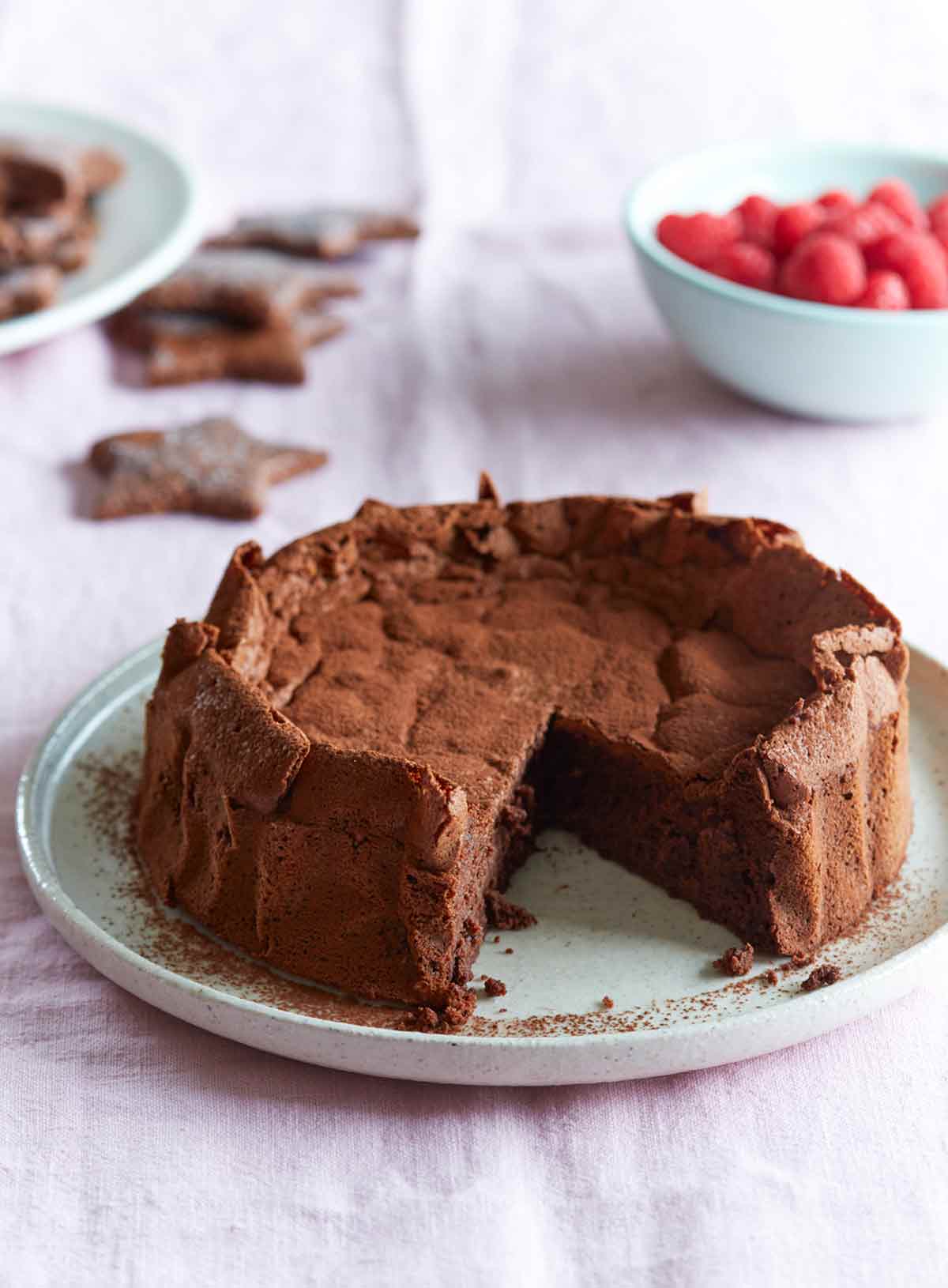 A whole chocolate meringue mousse cake with one slice cut from it.