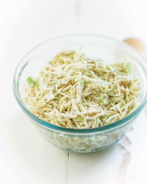 A glass bowl filled with creamy coleslaw.