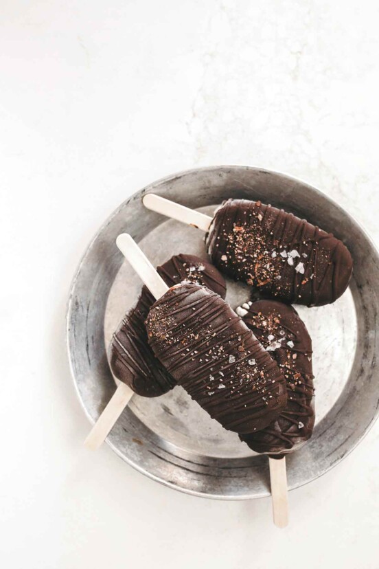 Four chocolate coated dairy-free ice cream bars in a metal bucket.
