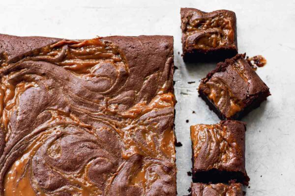 A slab of dulce de leche brownies, with five brownies cut from the end.