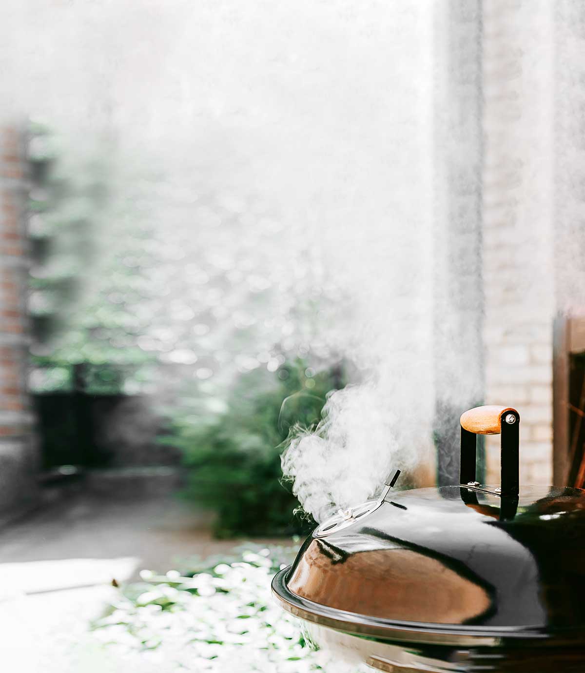 Smoke coming from a kettle grill that has been turned into a smoker.