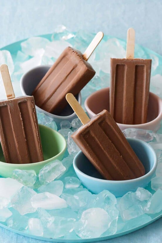 Four Mexican chocolate pops in colored bowls in a tray of ice.
