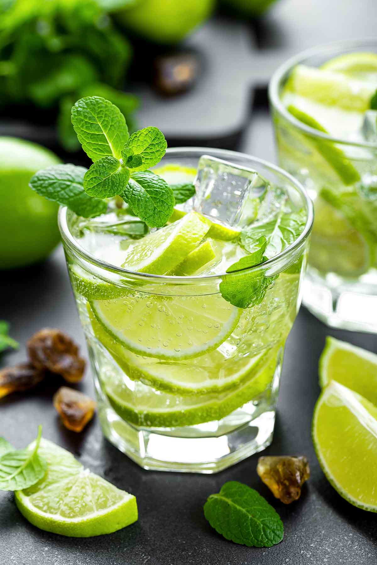 A glass of Mexican mojito with lime slices floating in it and a mint sprig garnish.