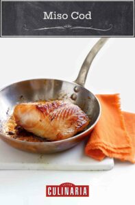 A piece of miso cod in a skillet with an orange napkin next to it.