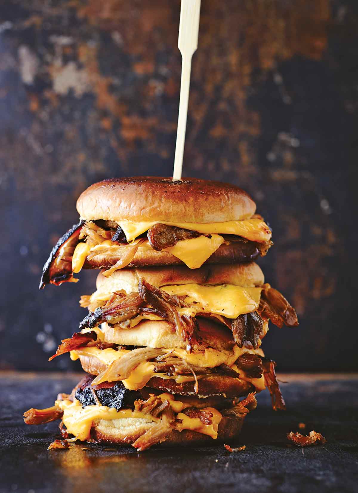 Three pulled pork grilled cheese sandwiches stacked on top of each other and secured with a wooden skewer.