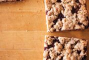 Four individual raspberry oatmeal bars on a wooden surface.