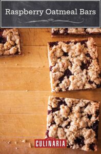 Four individual raspberry oatmeal bars on a wooden surface.