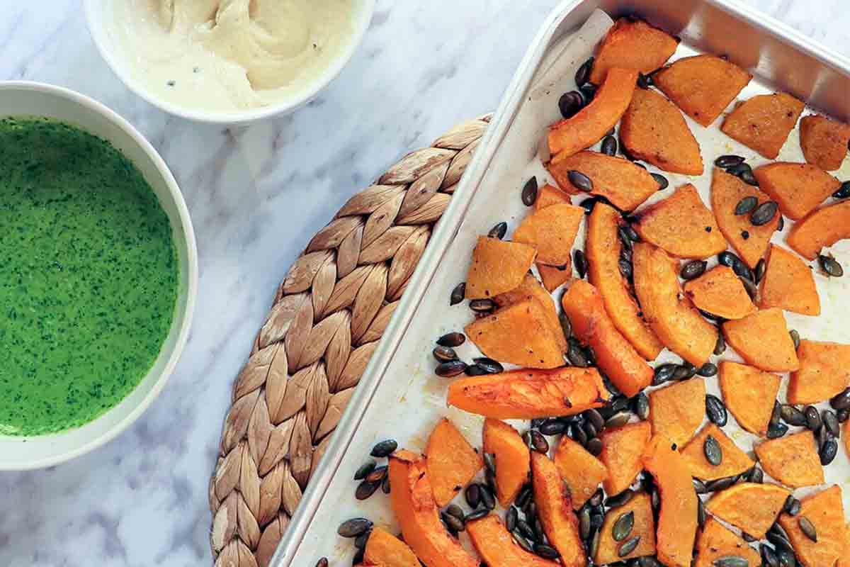 A baking sheet with roasted butternut squash with cilantro-lime granita in a bowl on the side.