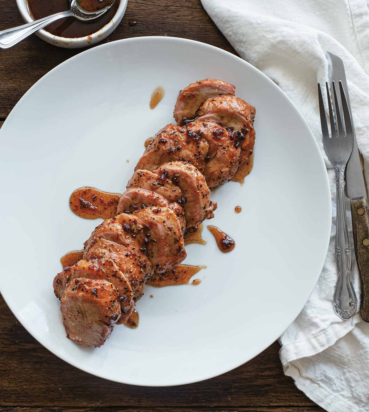 A sliced smoked pork tenderloin with maple chipotle glaze on a white plate.