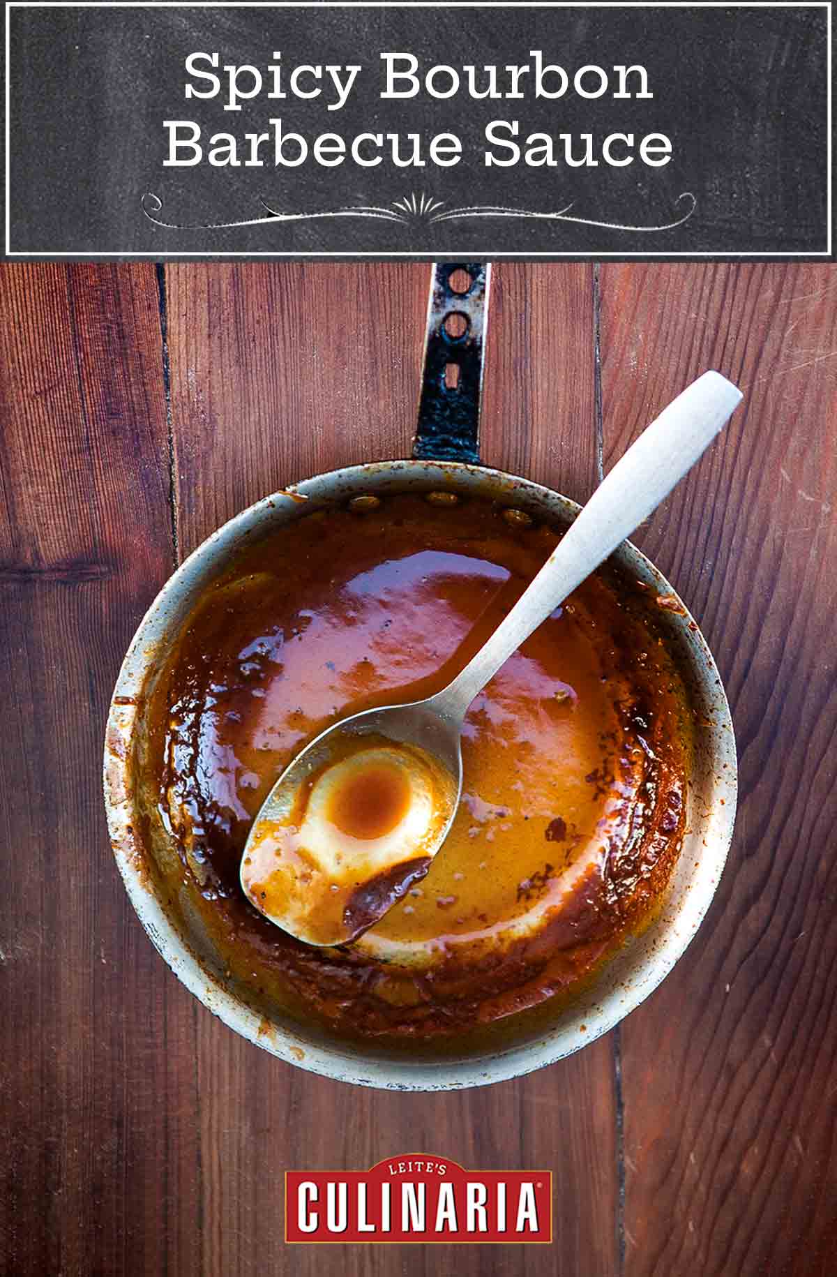 A small pot with a small amount of spicy bourbon barbecue sauce left in it and a spoon resting inside.