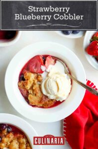 Two white bowls filled with strawberry blueberry cobbler and topped with ice cream.