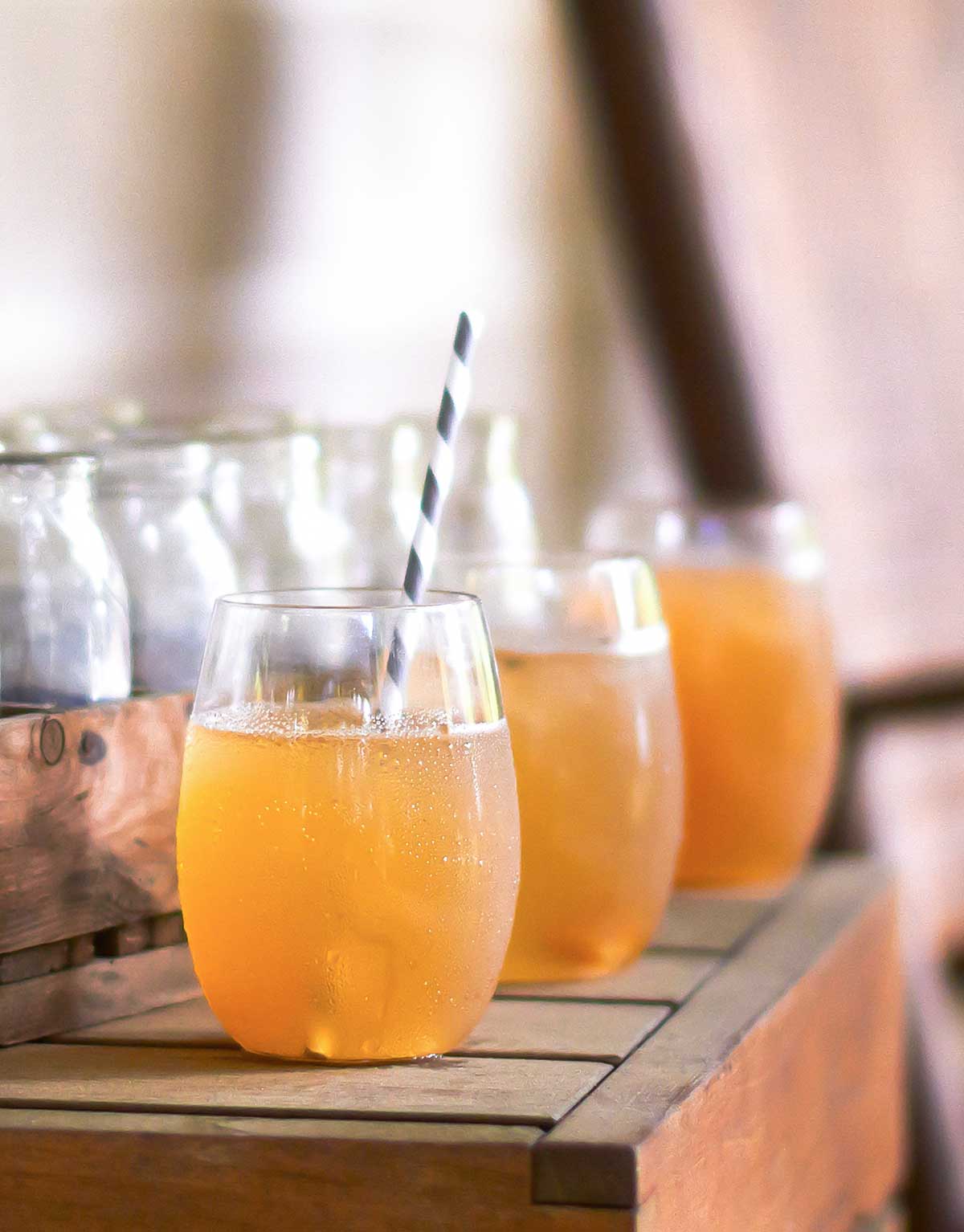 Three glasses of sweet tea cocktail on a wooden table.