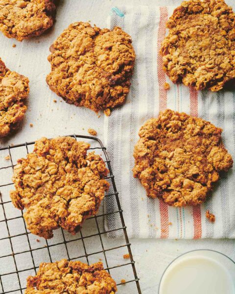 Seven vanilla bean oatmeal cookies scattered across a cooling rack and kitchen towel.