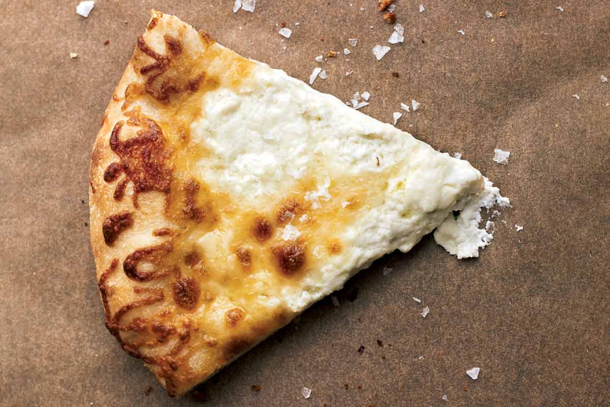 A wedge of white pizza on a piece of parchment.