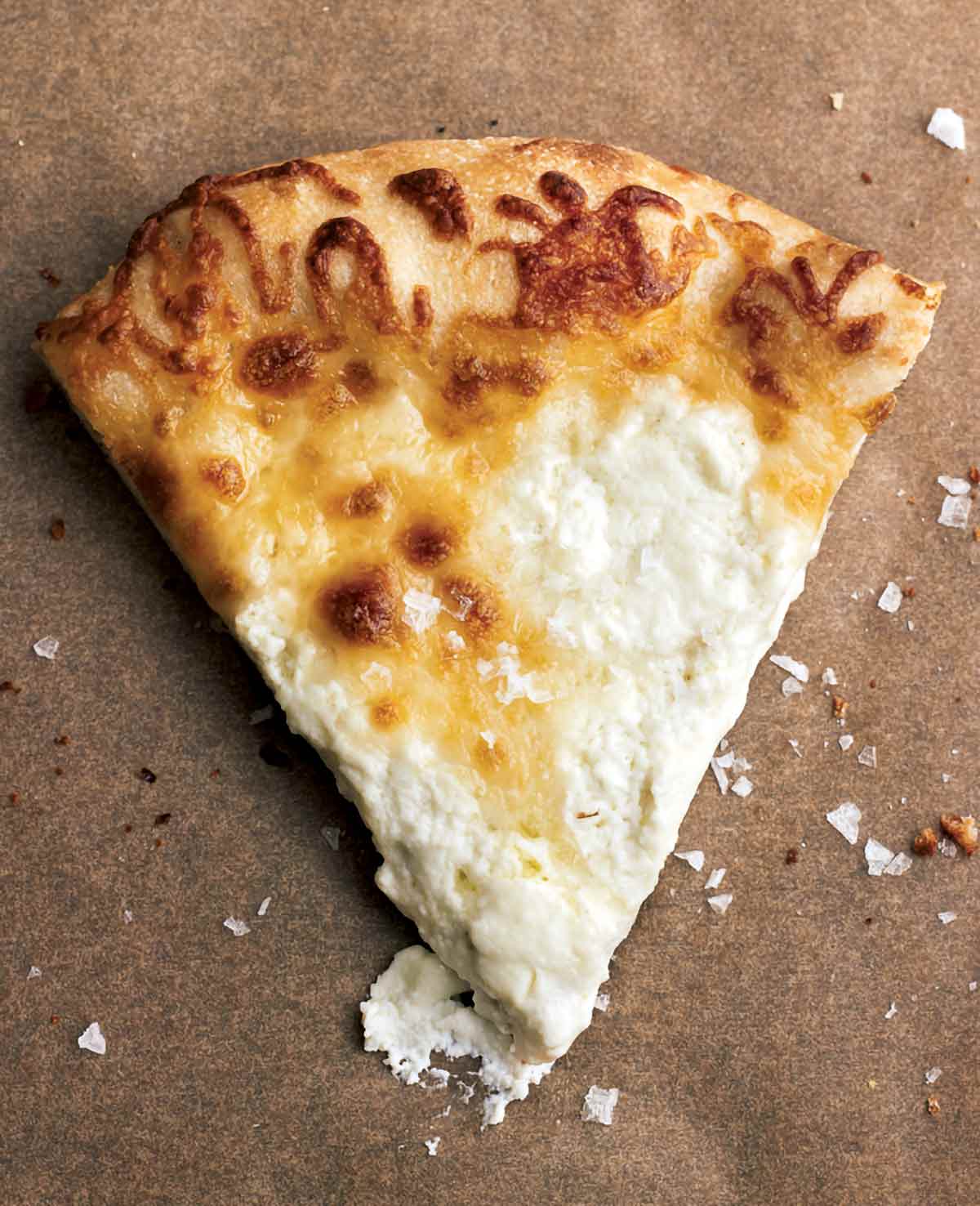 A slice of white pizza on a piece of parchment.