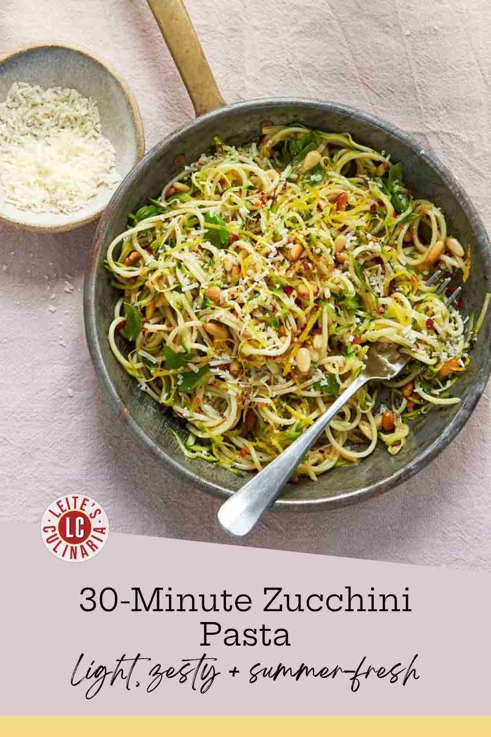 Grated zucchini and spaghetti tossed with lemon zest, basil, and toasted pine nuts in a rustic skillet.