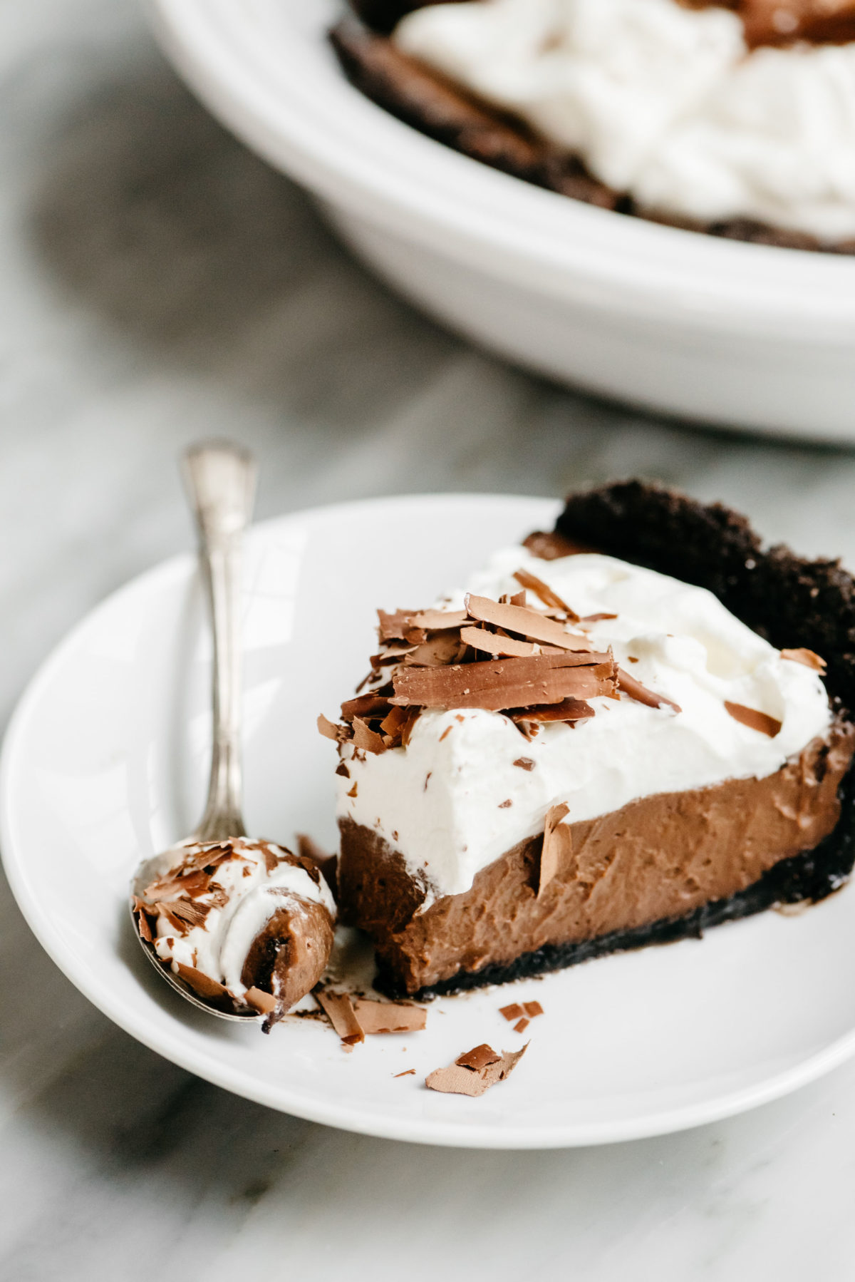 A slice of chocolate cream pie with a fork filled with a bite of pie.