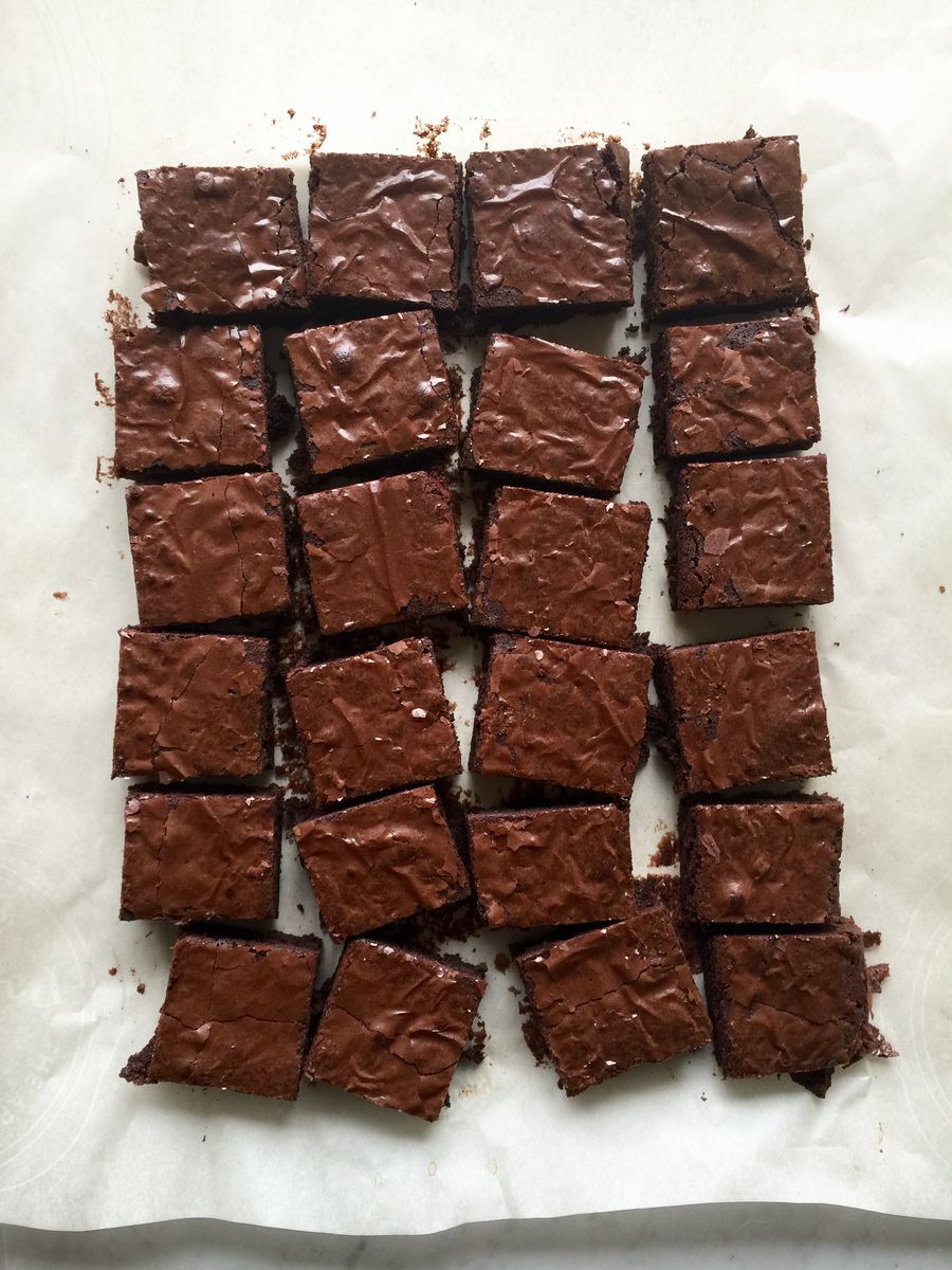 24 dark chocolate brownies on a sheet of parchment.