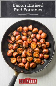 A frying pan filled with halved red potatoes that are browned and covered with crispy bacon and thyme.